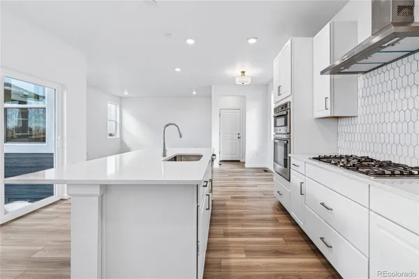 a large kitchen with stainless steel appliances kitchen island a large counter top and a stove top oven