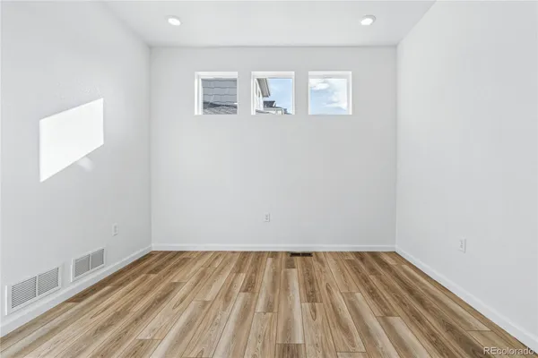 a kitchen with stainless steel appliances granite countertop a sink a stove a refrigerator a microwave oven with white cabinets and wooden floor