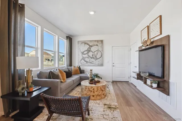 a living room with furniture a flat screen tv and a large window