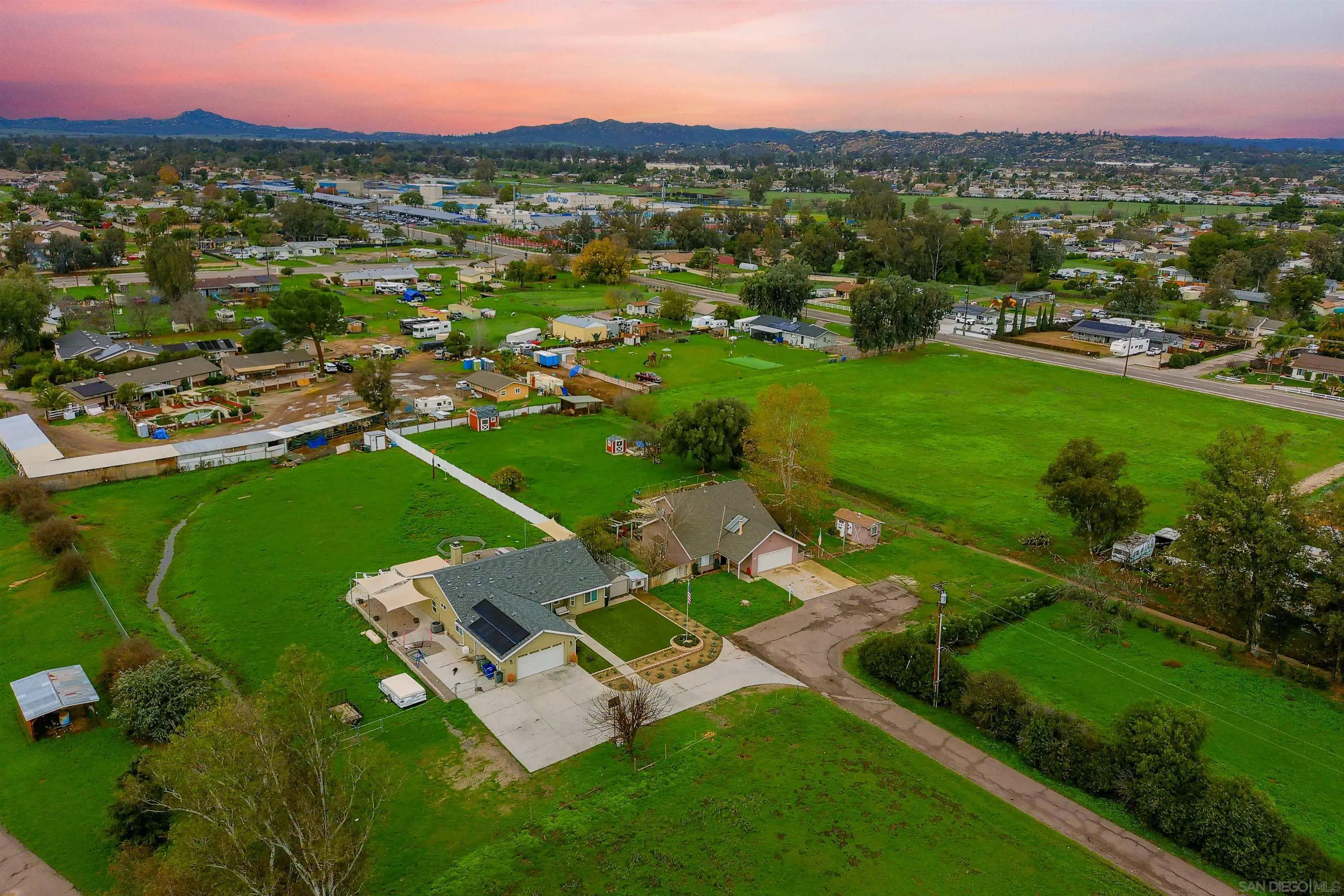 an aerial view of residential houses with outdoor space and trees