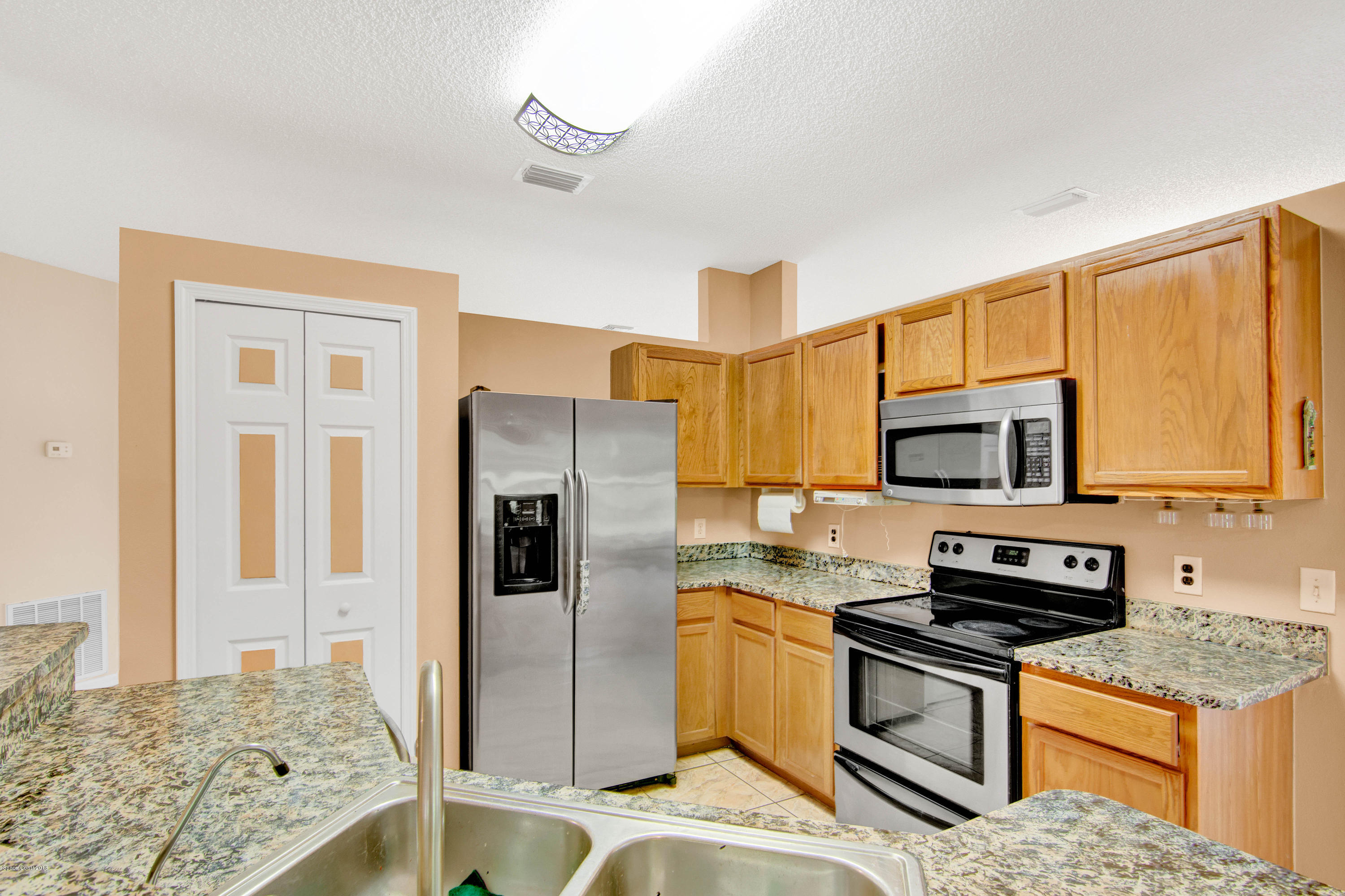 1030 Meadowbrook Road Northeast Palm Bay, FL 32905 - Photo 3 of 24 a kitchen with stainless steel appliances granite countertop a refrigerator stove and microwave