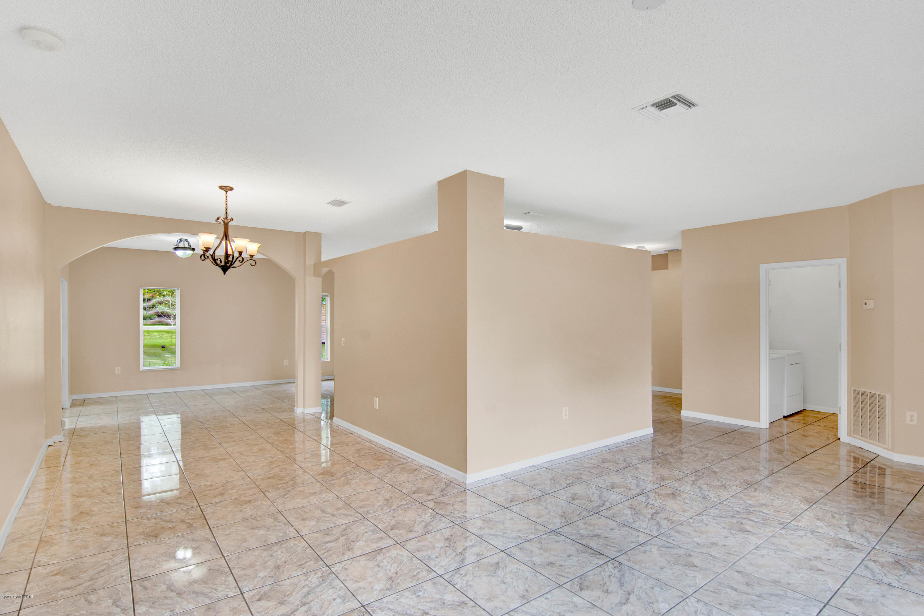 1030 Meadowbrook Road Northeast Palm Bay, FL 32905 - Photo 7 of 24 a view of a room with a chandelier fan and windows
