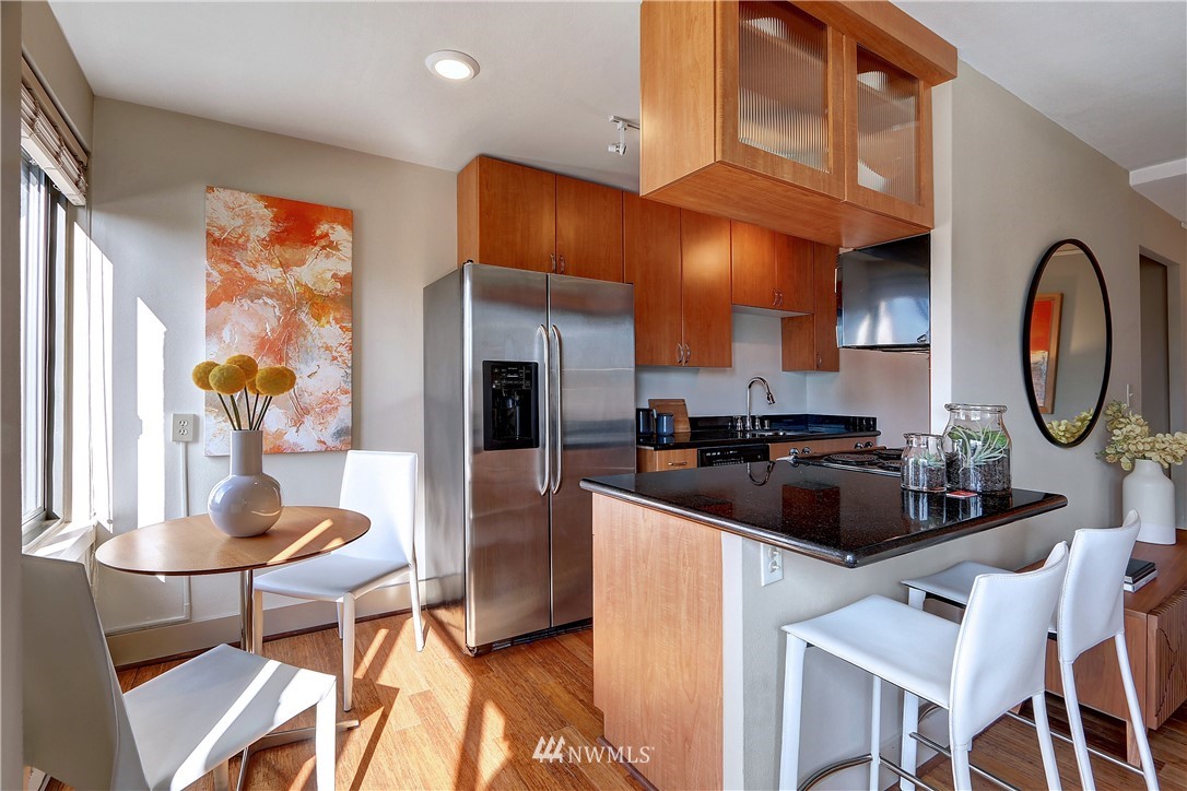 1105 Spring Street, Unit 610 Seattle, WA 98104 - Photo 7 of 12 a kitchen with stainless steel appliances a dining table and chairs