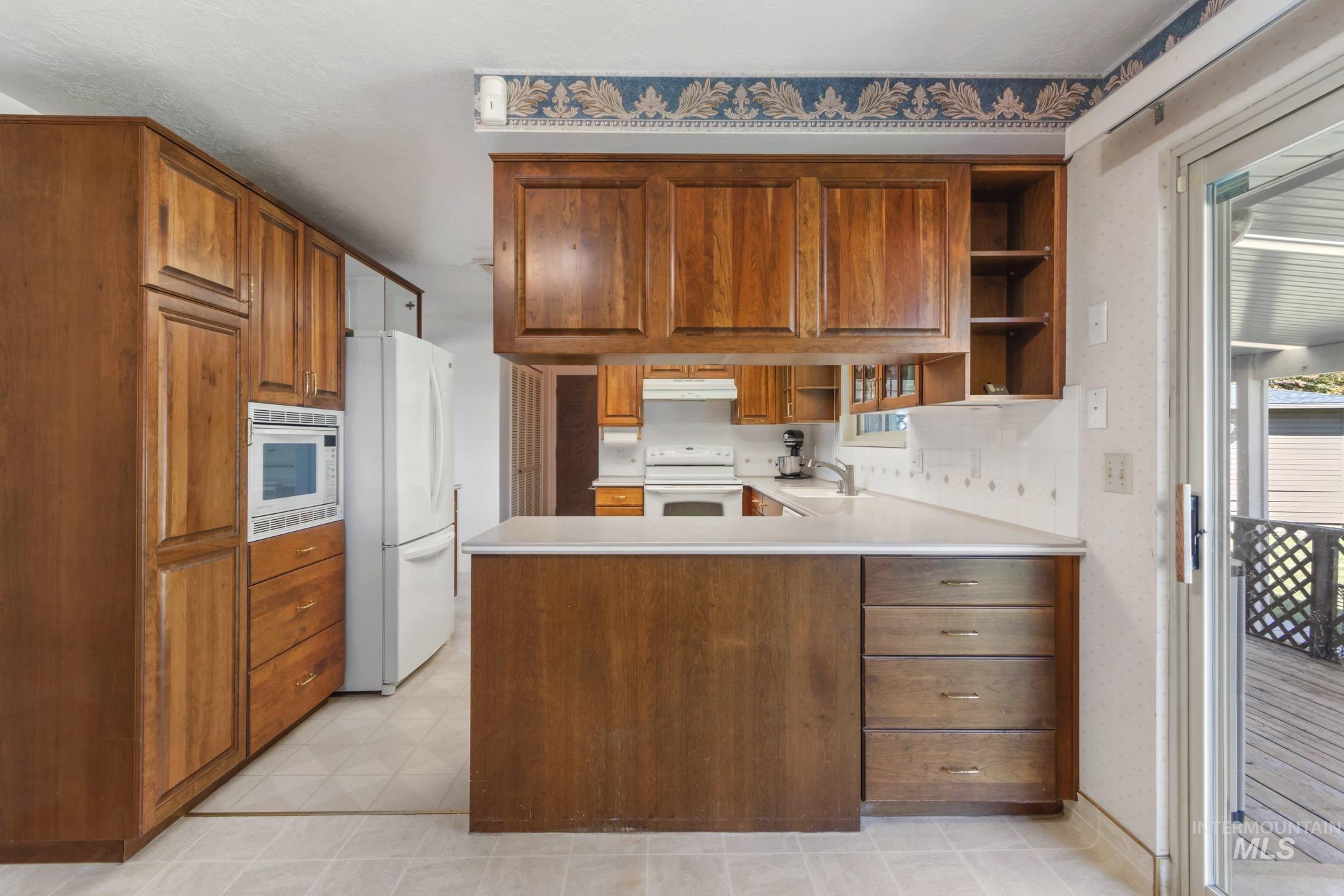 11360 West Lake Hazel Road Boise, ID 83709 - Photo 23 of 50 Wood cabinetry with a built-in display, white countertops, and a tile backsplash
