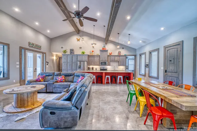 a open kitchen with stainless steel appliances granite countertop a stove dining table chairs cabinets and a counter space