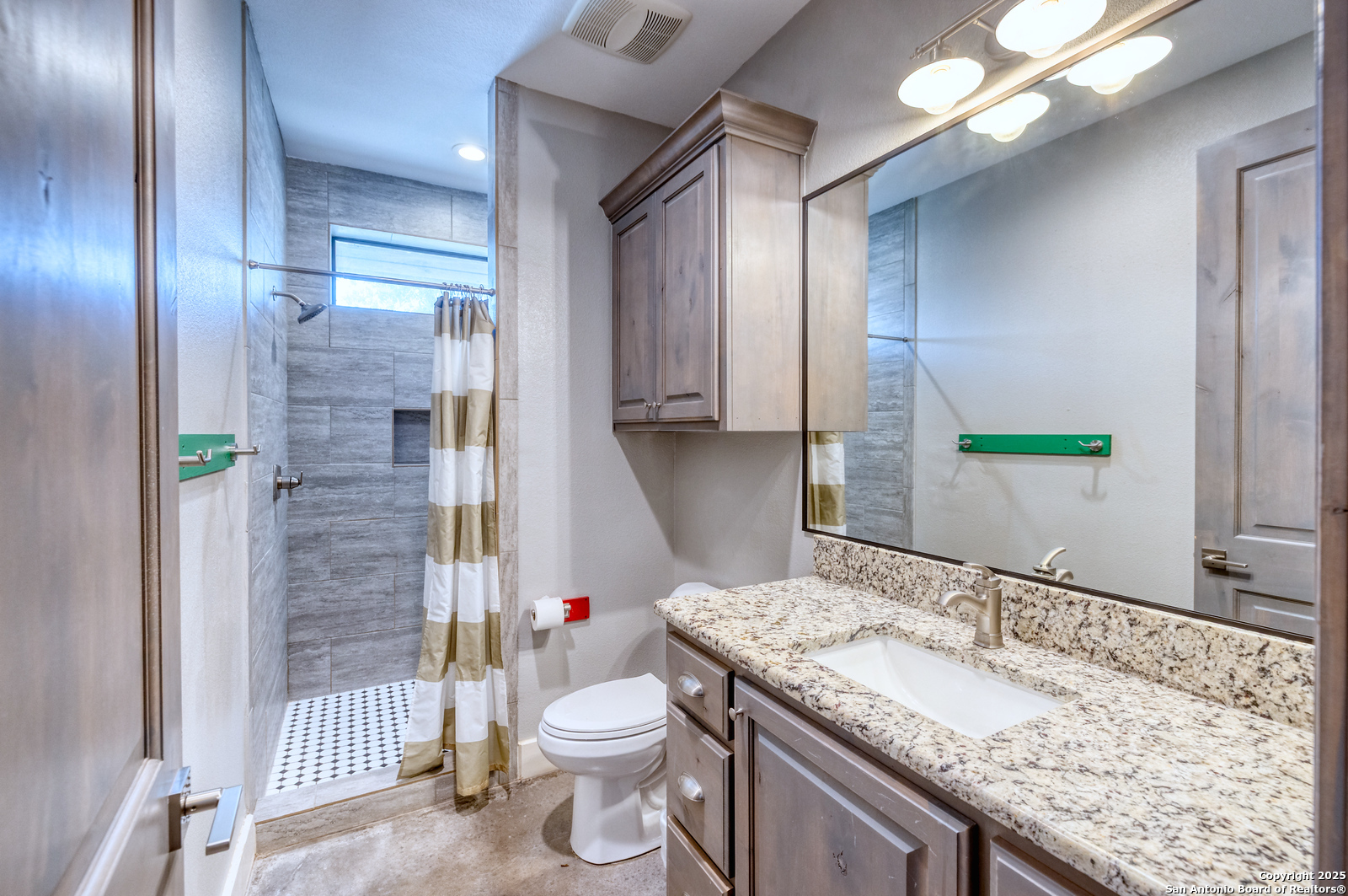 989 Mountain Valley Road Concan, TX 78838 - Photo 21 of 35 a bathroom with a granite countertop sink a toilet a mirror and shower