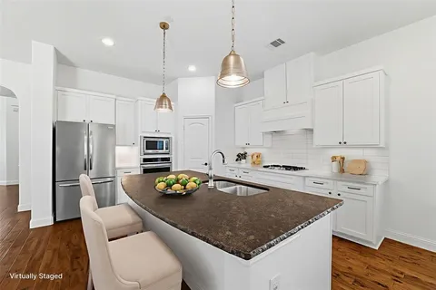 a kitchen with stainless steel appliances granite countertop a sink refrigerator and cabinets