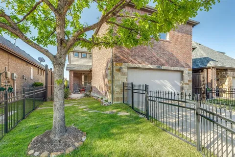 a view of a house with a yard and a large tree