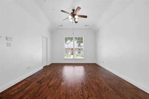 an empty room with wooden floor chandelier fan and windows