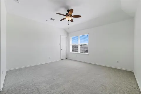 an empty room with ceiling fan and window