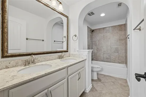a bathroom with a granite countertop sink a toilet and a large mirror