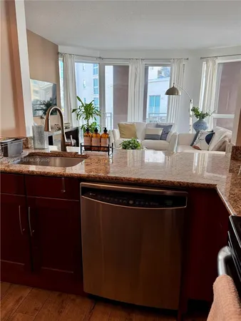 a kitchen with granite countertop a sink a window stainless steel appliances and cabinets