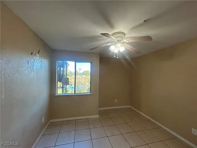 en empty room with windows and chandelier fan