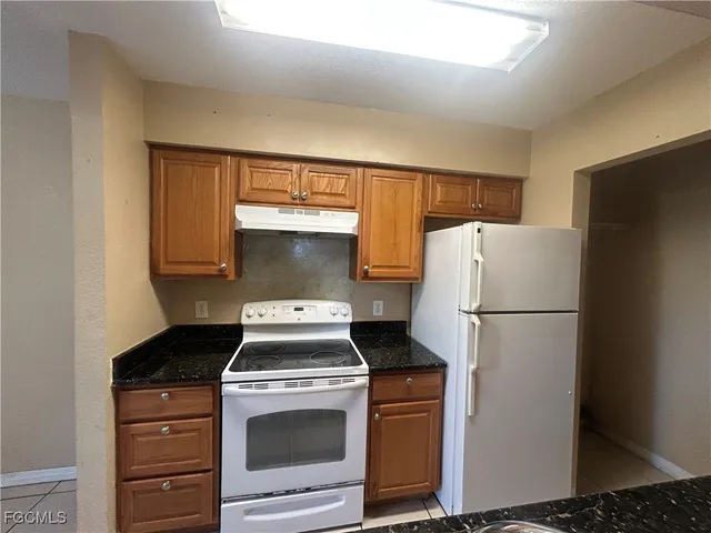 a white refrigerator freezer and a stove sitting inside of a kitchen