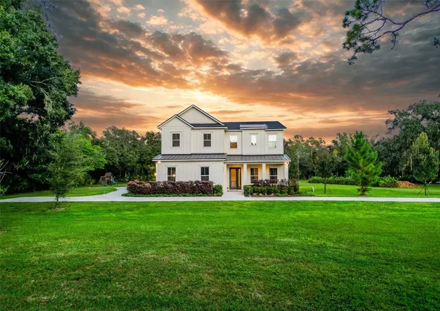 a view of a house with a big yard and large trees