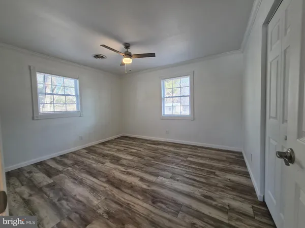 a view of an empty room and window and chandelier fan