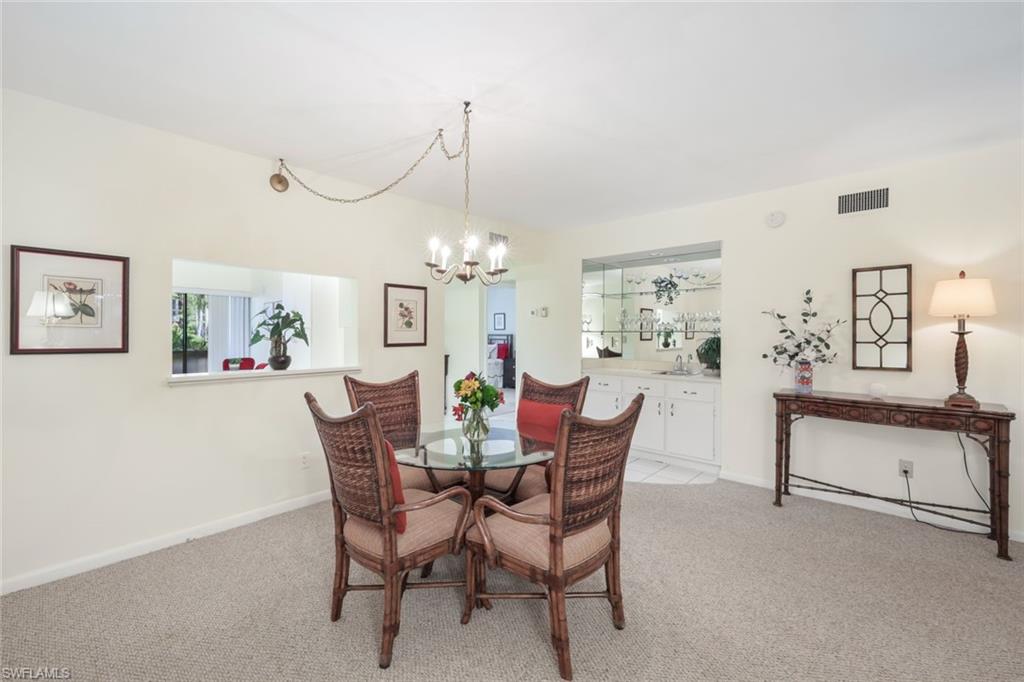 1814 Kings Lake Boulevard, Unit 102 Naples, FL 34112 - Photo 5 of 21 Carpeted dining area featuring a notable chandelier