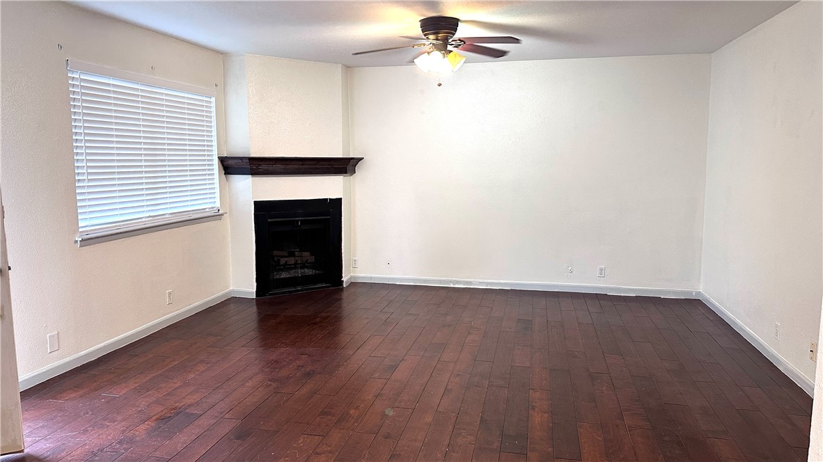 1932 Hidden Way Corpus Christi, TX 78412 - Photo 2 of 14 an empty room with wooden floor a ceiling fan a fireplace and windows