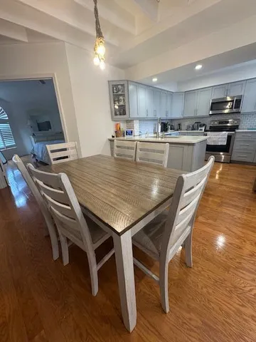 a dining table with wooden floor and kitchen view