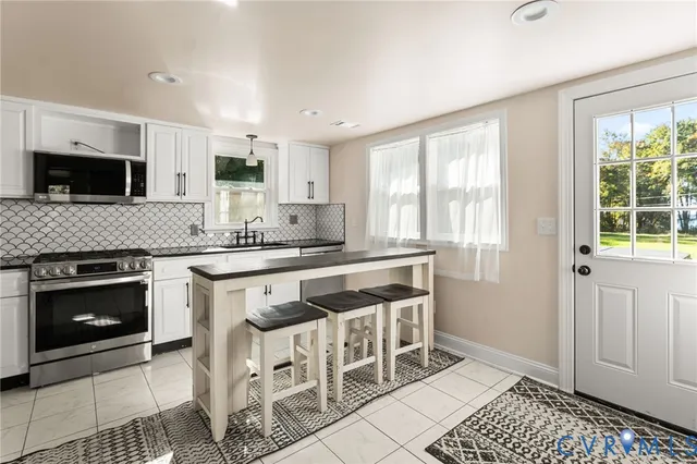 a kitchen with stainless steel appliances granite countertop a stove a sink and a microwave