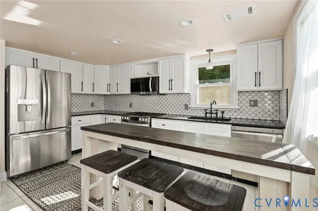 a kitchen with kitchen island granite countertop a sink stove and refrigerator