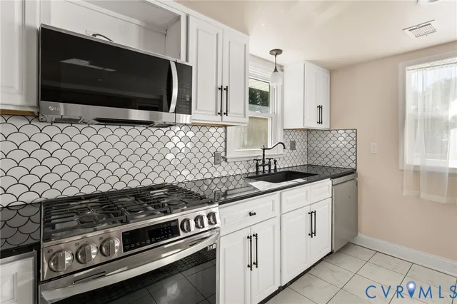 a kitchen with stainless steel appliances a stove a microwave a sink and cabinets