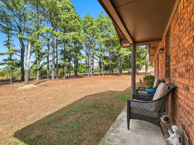 30063 South 4300th Road Stigler, OK 74462 - Photo 33 of 58 Brick exterior with an expansive lawn, mature trees, and a covered concrete patio