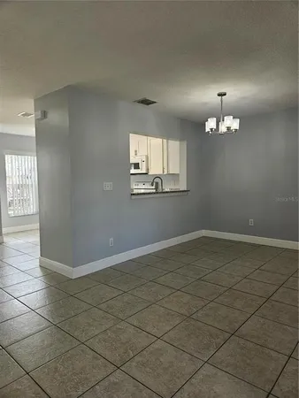 an empty room with chandelier fan and windows
