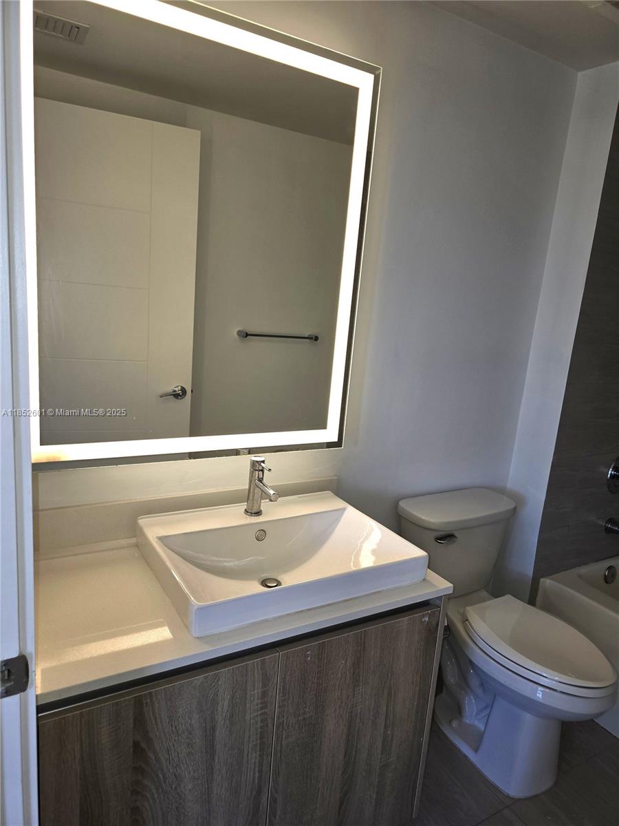 2960 Northeast 207th Street, Unit 713 Aventura, FL 33180 - Photo 23 of 33 a bathroom with a sink vanity mirror and toilet
