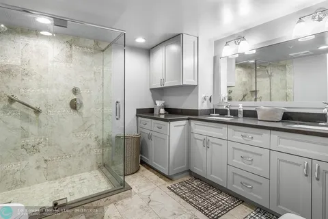 a bathroom with a toilet a sink a glass door shower and mirror