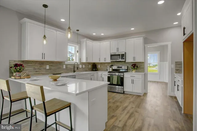 a kitchen with a sink a center island stainless steel appliances and cabinets
