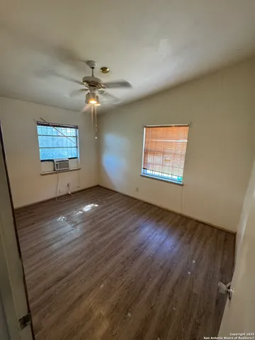 en empty room with windows and ceiling fan