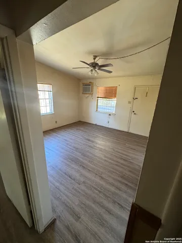 a view of a big room with wooden floor and a ceiling fan