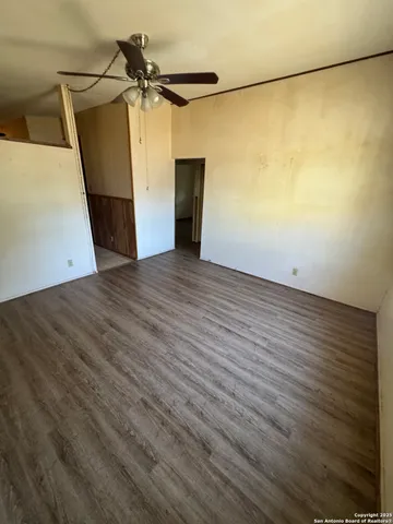 an empty room with wooden floor and a ceiling fan