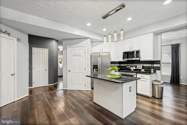 a kitchen with stainless steel appliances kitchen island a refrigerator sink and microwave