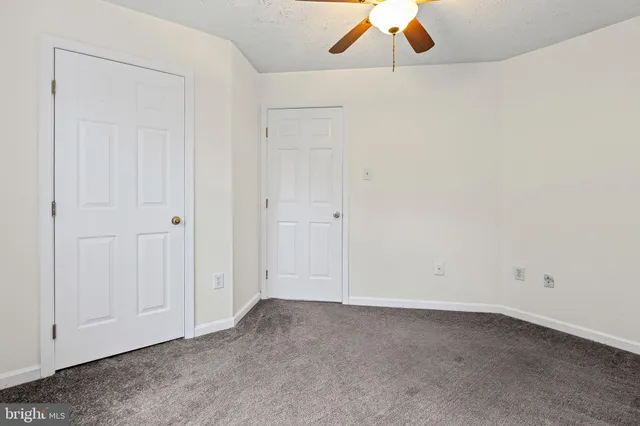an empty room with a ceiling fan and wooden floor