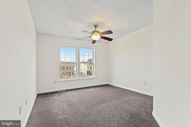 an empty room with a window and a fan
