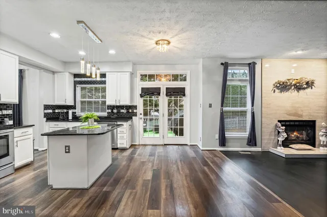 a kitchen with granite countertop a stove top oven a sink dishwasher and a fireplace with wooden floor