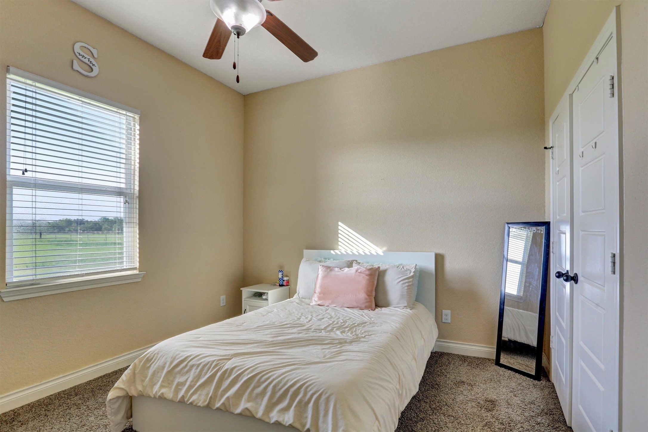 8131 Brinkmeyer Road Needville, TX 77461 - Photo 22 of 49 Cozy bedroom with natural light, featuring a comfortable bed, soft carpeting, and a ceiling fan for added comfort.