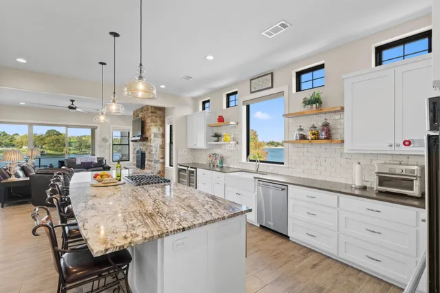 a kitchen with stainless steel appliances granite countertop stove top oven a sink dishwasher and white cabinets with wooden floor