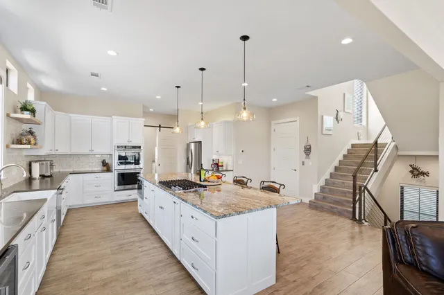 a large white kitchen with a large center island attached withe living room