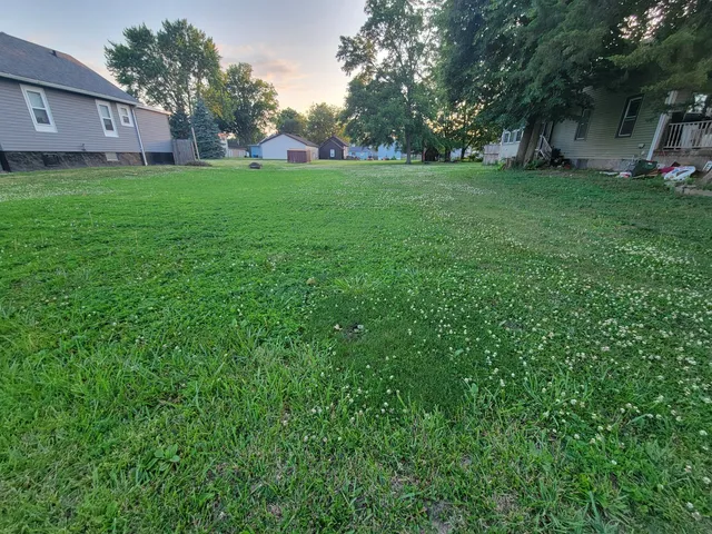 a view of a house with a big yard and large trees