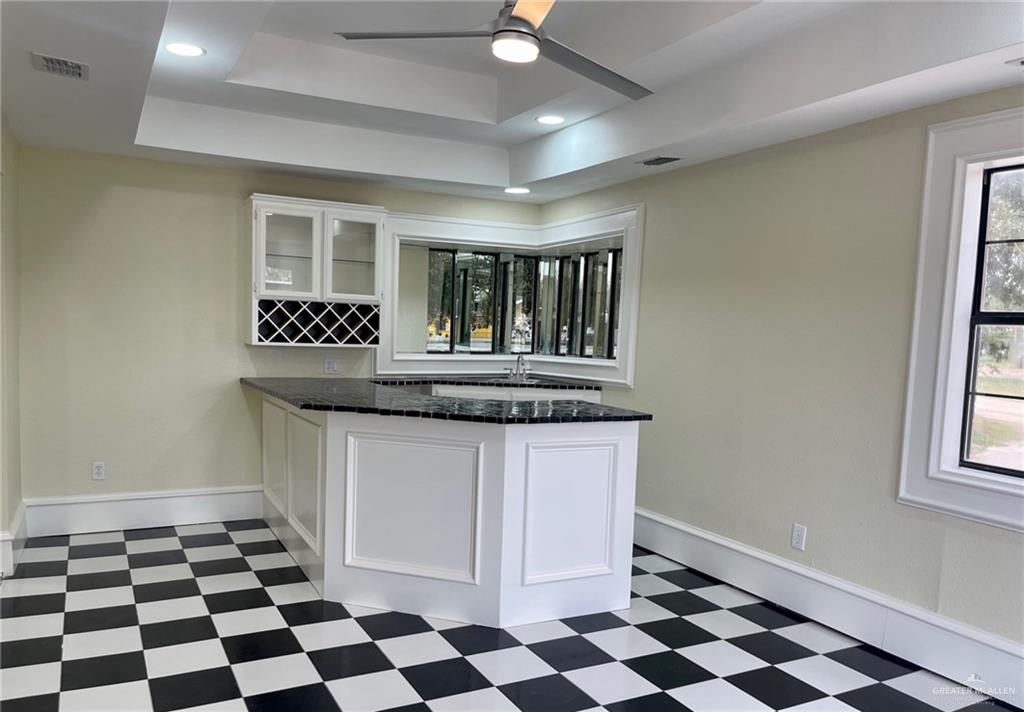 5307 Fm 493 Road Donna, TX 78537 - Photo 16 of 27 Kitchen featuring dark stone counters, dark tile flooring, ceiling fan, a tray ceiling, and white cabinets