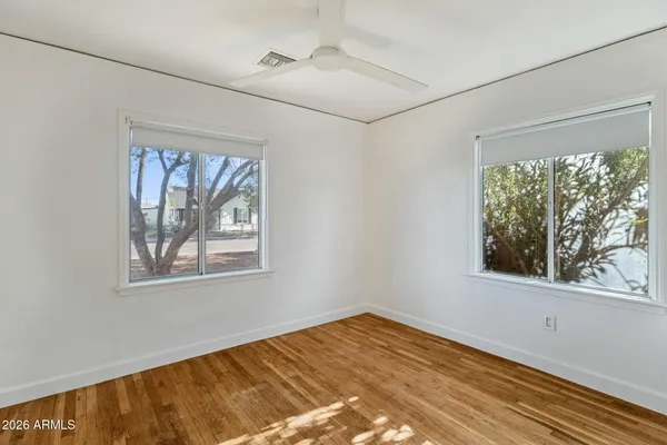 a view of empty room with wooden floor and fan