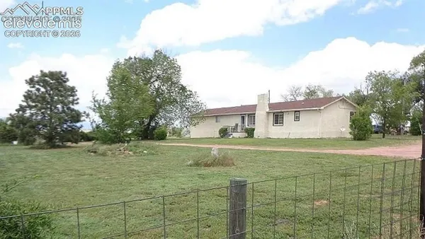 a view of a house with backyard and trees