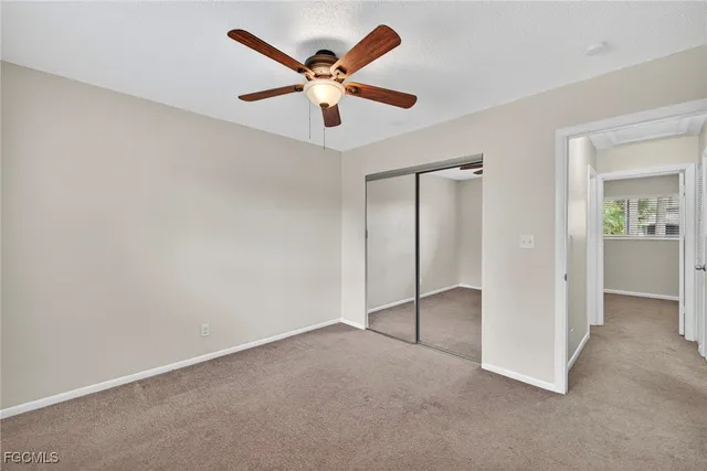 an empty room with closet and a ceiling fan