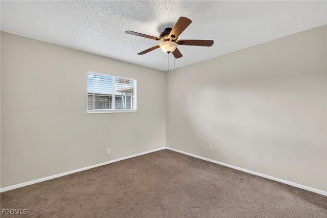 an empty room with a window and a ceiling fan