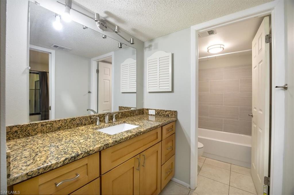 3635 Boca Ciega Drive, Unit 207 Naples, FL 34112 - Photo 12 of 24 a bathroom with a granite countertop sink and a mirror