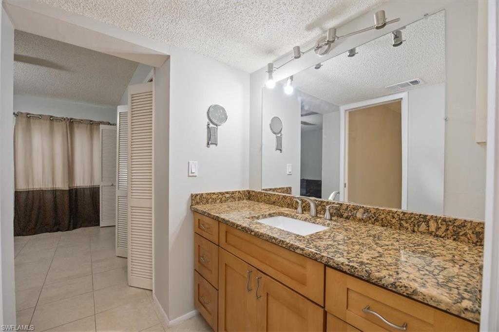 3635 Boca Ciega Drive, Unit 207 Naples, FL 34112 - Photo 13 of 24 a bathroom with a granite countertop sink and a mirror