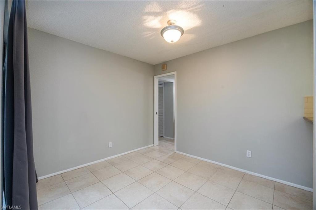 3635 Boca Ciega Drive, Unit 207 Naples, FL 34112 - Photo 14 of 24 an empty room with a chandelier fan and windows